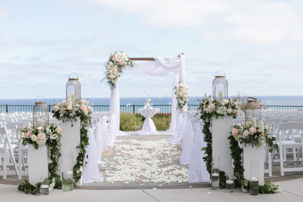 Wood arch with white sheers with florals in white and blush at the Heritage Park in Dana Point, CA.