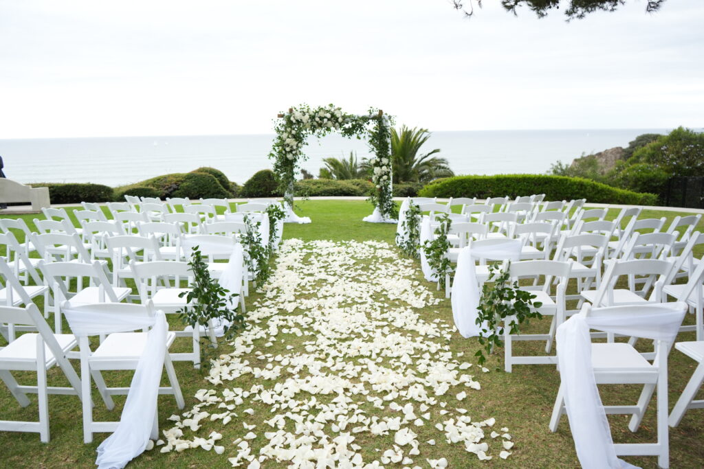 Pines Park in Dana Point wedding ceremony. Arch covered with greens lots of petals down the aisle.